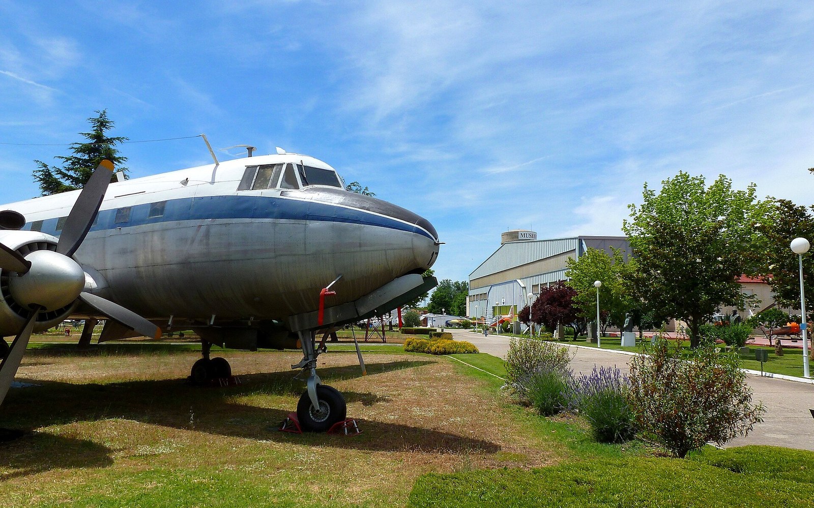 Vintage propeller aircraft displayed outdoors on grass near a museum building